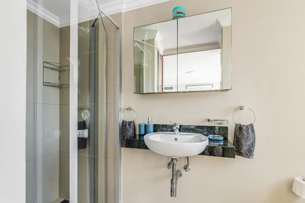 Modern bathroom with round white sink, mirror, and glass shower enclosure