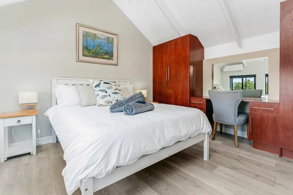 Bright bedroom with white bed, wooden wardrobe, and desk area