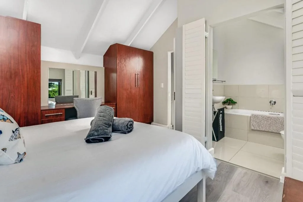 Bright bedroom with ensuite bathroom, wooden wardrobe, and vanity mirror