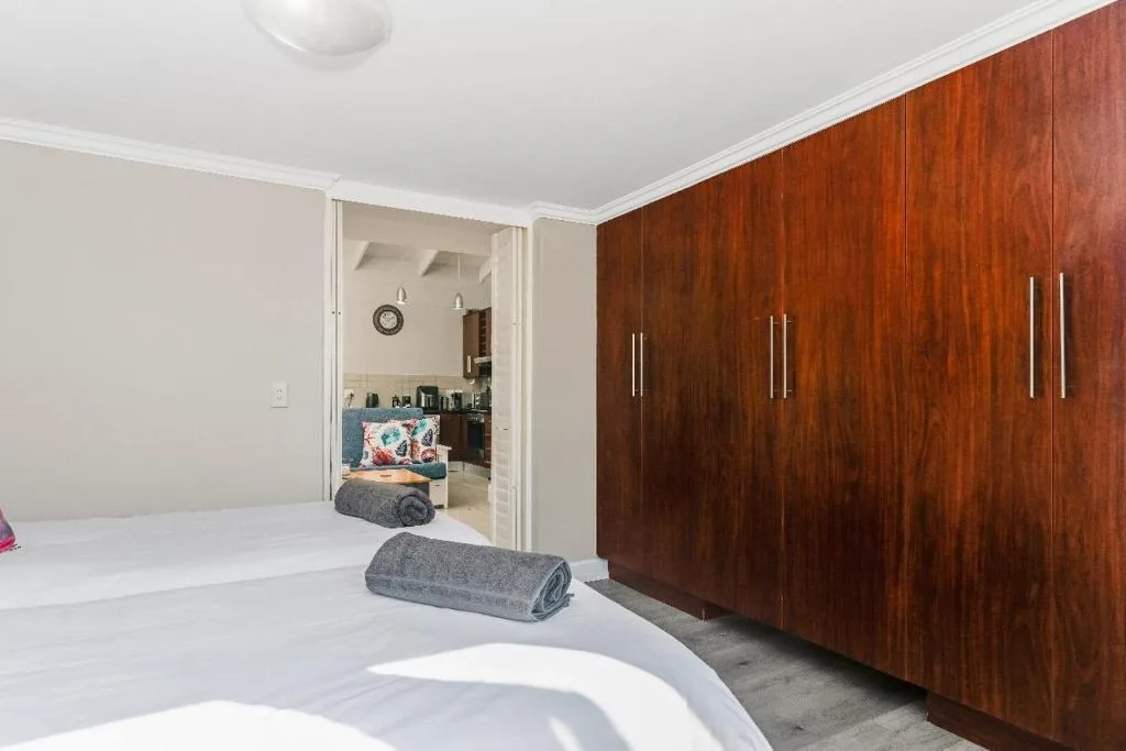Spacious bedroom with white bedding and large wooden wardrobe storage