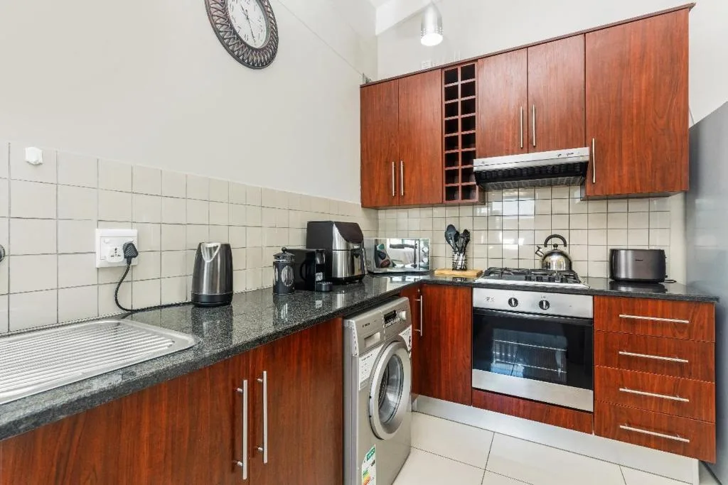 Modern kitchen with wooden cabinetry, granite countertops, gas stove, and washing machine