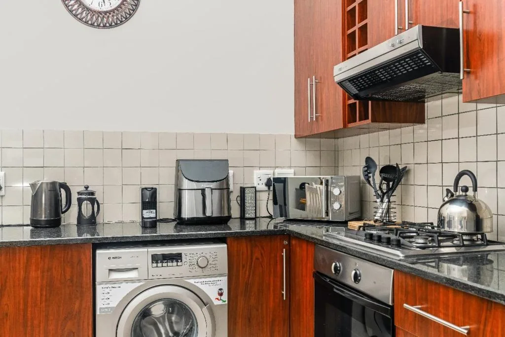 Modern kitchen with wood cabinetry, stove, microwave, and countertop appliances