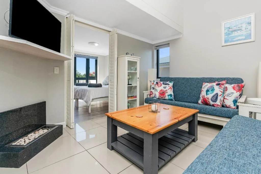 Modern lounge with teal sofa, wooden coffee table, and fireplace