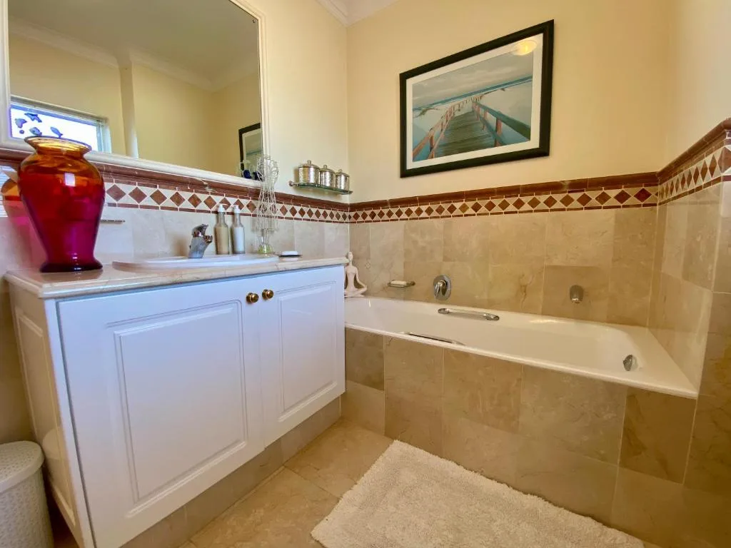 Spacious bathroom with white vanity, bathtub, and decorative tile border