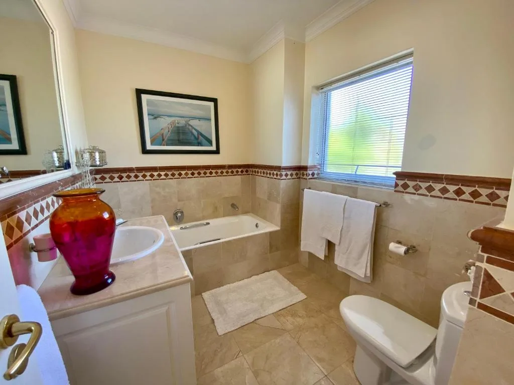 Spacious bathroom with vanity, bathtub, toilet and decorative tile accents