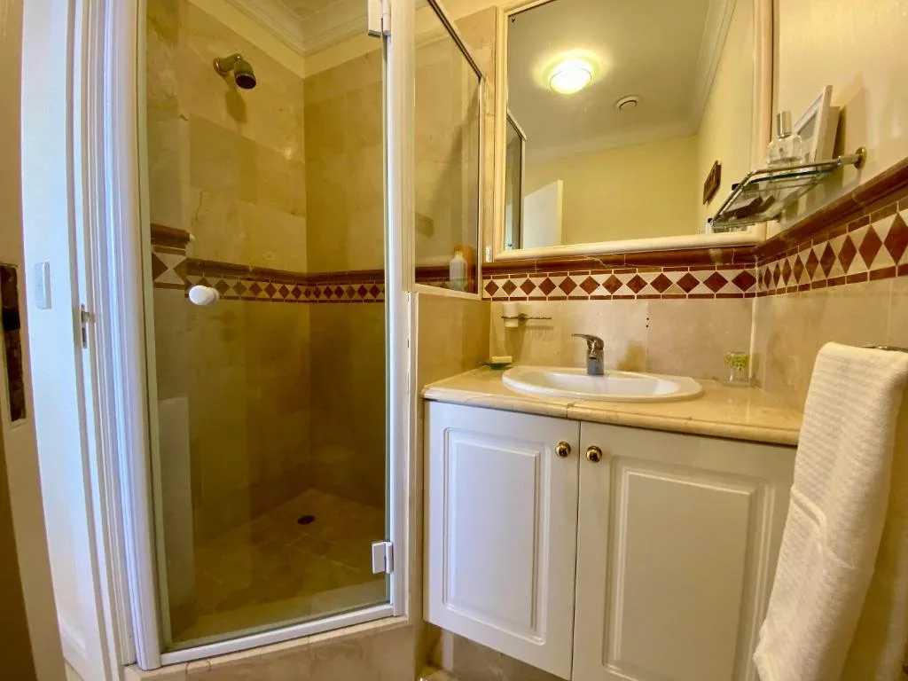 Bright bathroom with walk-in shower, vanity sink, and decorative tile border