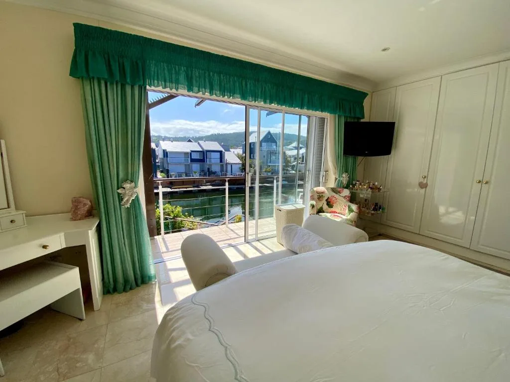 Bright bedroom with water views, green curtains, and deck access