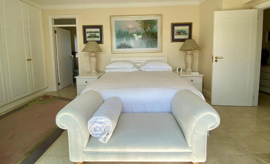 Spacious bedroom with double bed, cream furnishings, and nature artwork