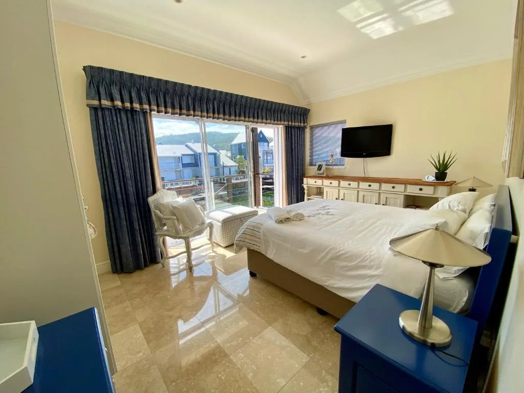 Bright bedroom with waterfront views through large glass doors and curtains