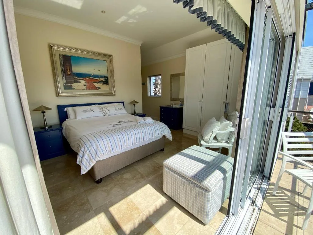 Spacious bedroom with queen bed, blue bedside tables, and deck access