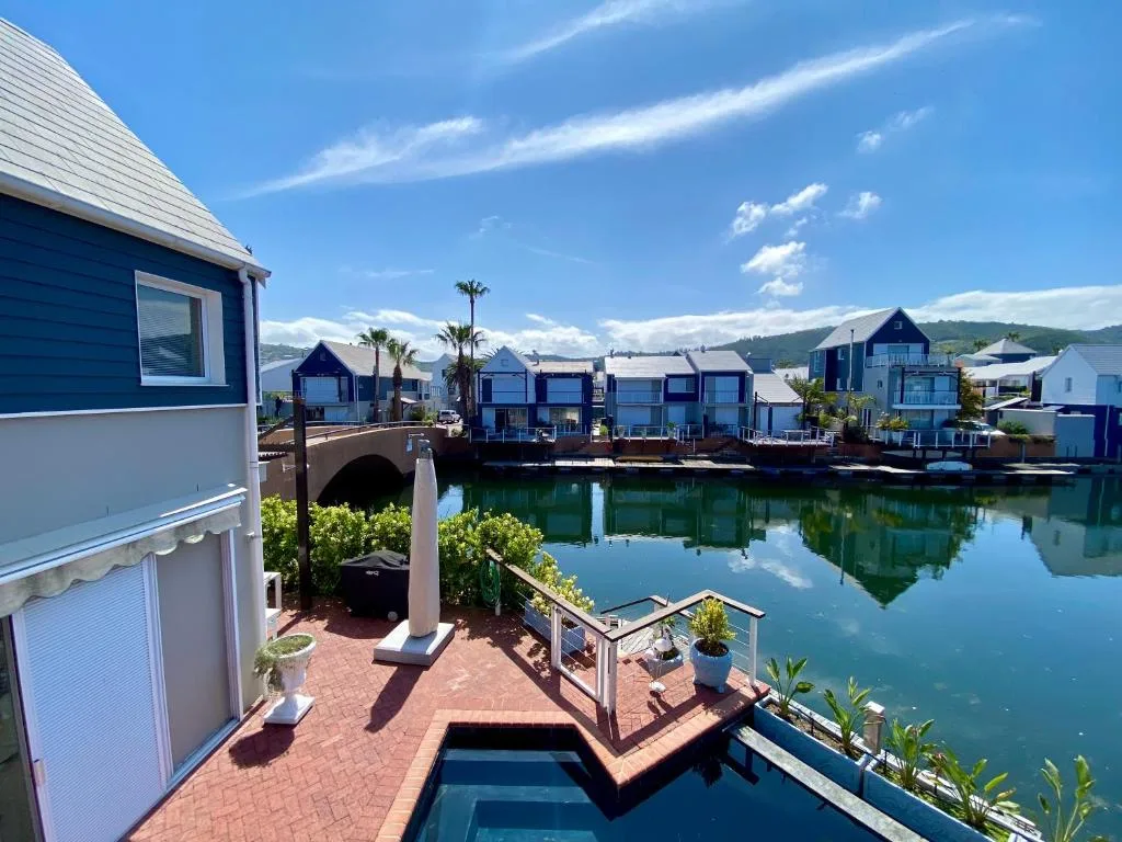 Waterfront deck with railing overlooking calm lagoon and blue boat houses
