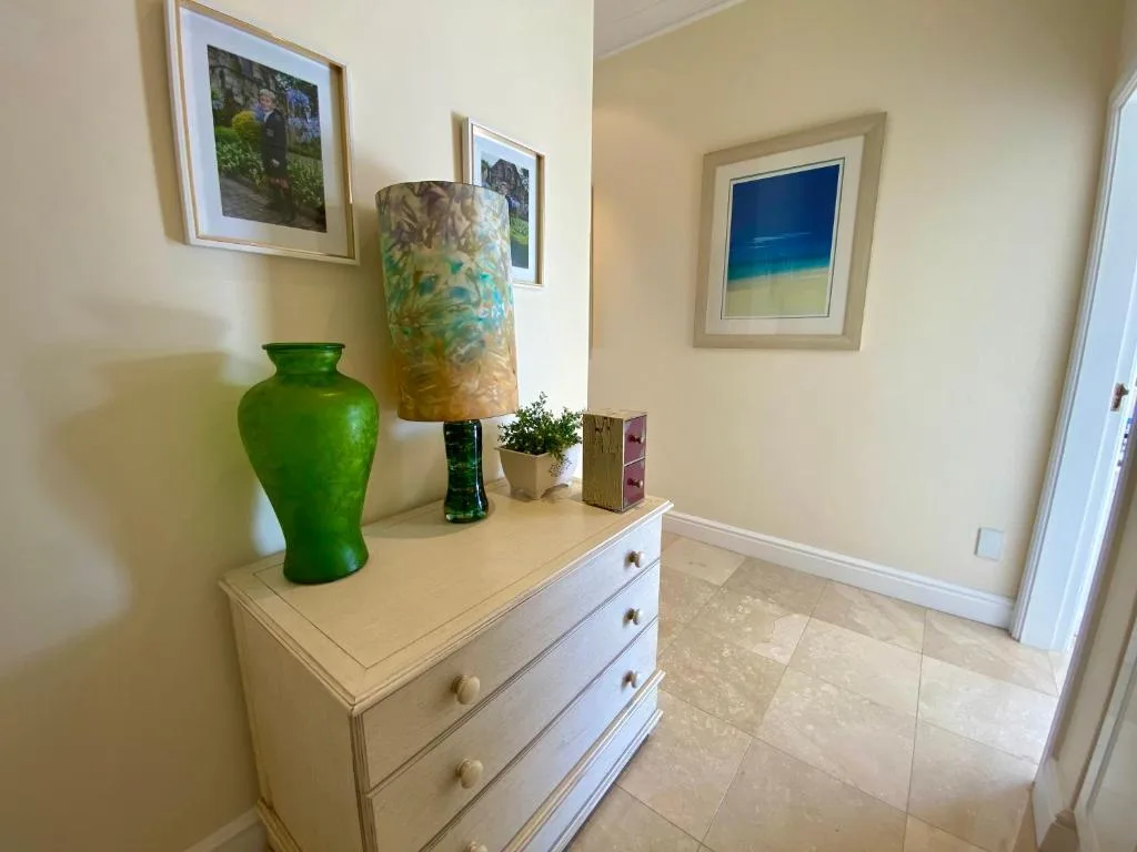 Hallway with white dresser, decorative vases, lamp, and framed artwork