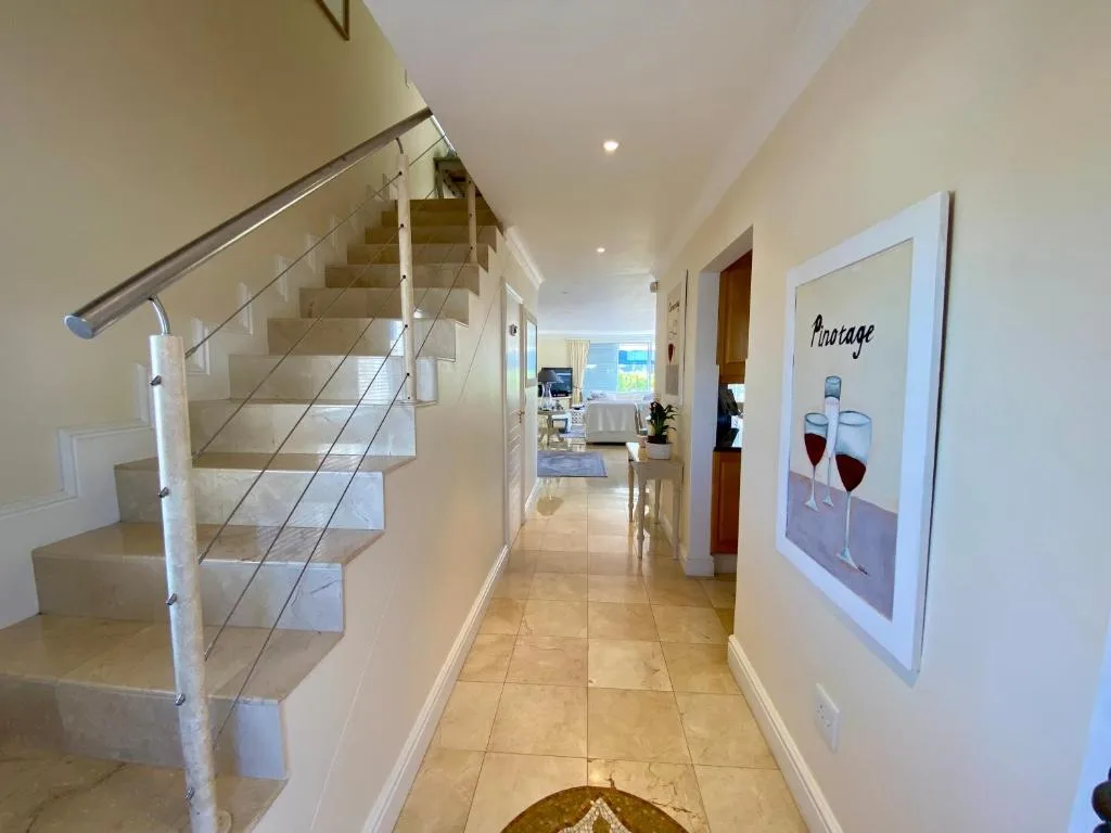 Modern hallway with staircase, wine artwork, and open plan living area
