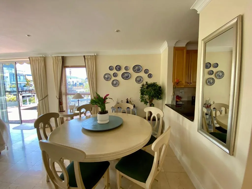 Bright dining room with oval white table and cream chairs overlooking water
