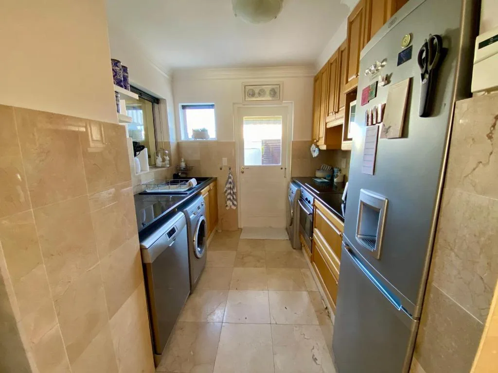 Galley kitchen with stainless steel appliances and wooden cabinetry