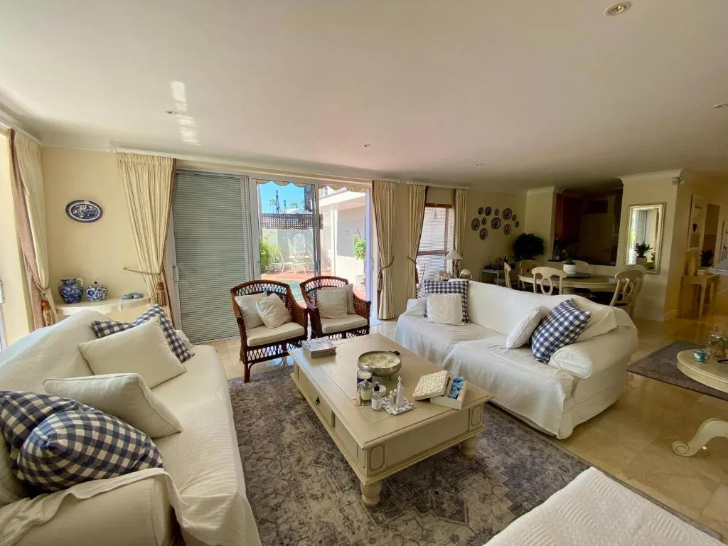 Spacious lounge with cream sofas, blue check cushions, and ocean view doors