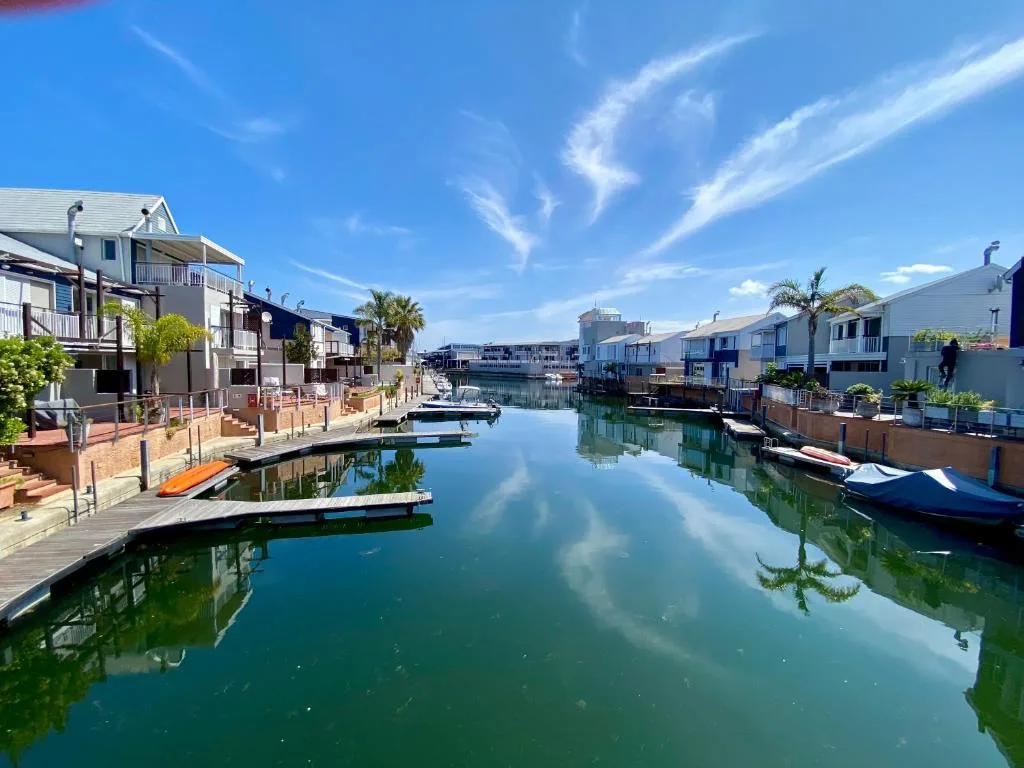 Serene canal waterfront with colorful houses and moored boats under blue sky