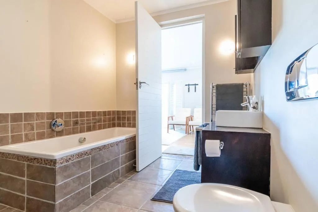 Modern bathroom with bathtub, vanity sink, and heated towel rack