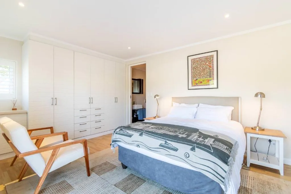 Spacious bedroom with queen bed, white wardrobes, and wooden accent chair