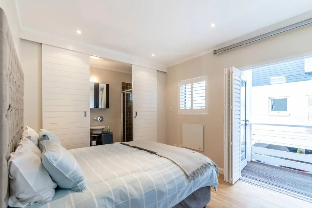 Modern bedroom with queen bed, en-suite bathroom, and patio doors to deck