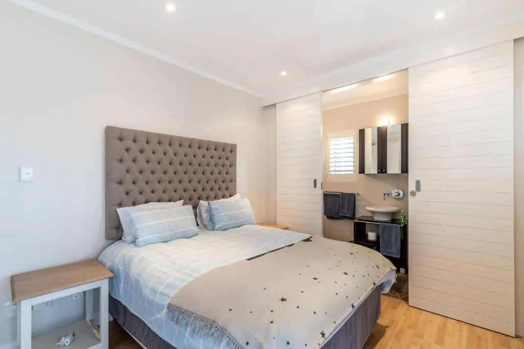 Modern bedroom with tufted headboard, en-suite bathroom visible in background