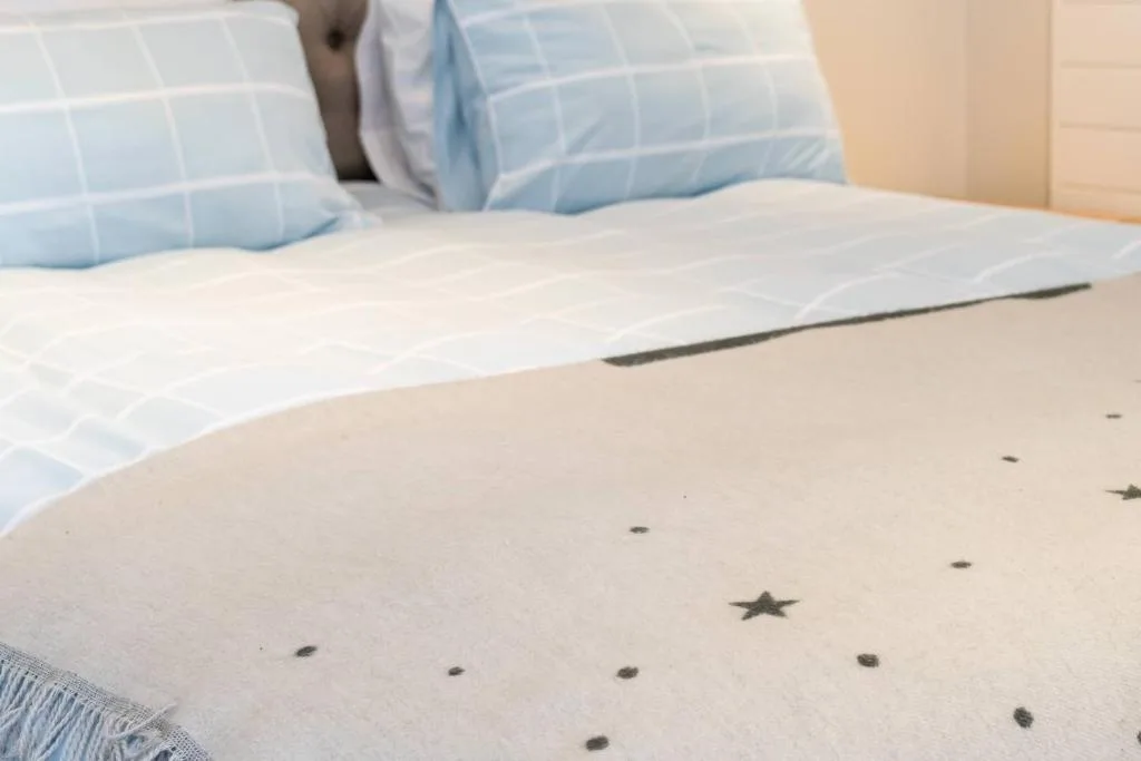 Clean bed with blue checkered pillows and star-patterned bedding