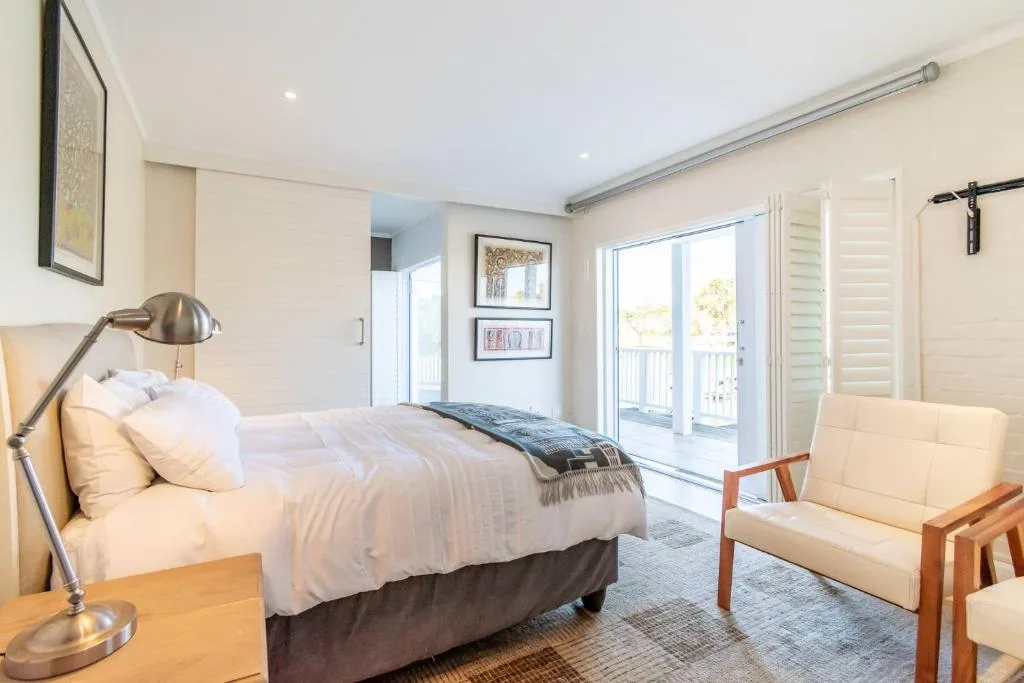 Bright bedroom with queen bed, armchair, and sliding doors to balcony