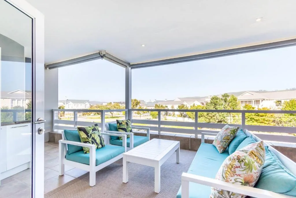 Spacious covered deck with turquoise seating and scenic residential views