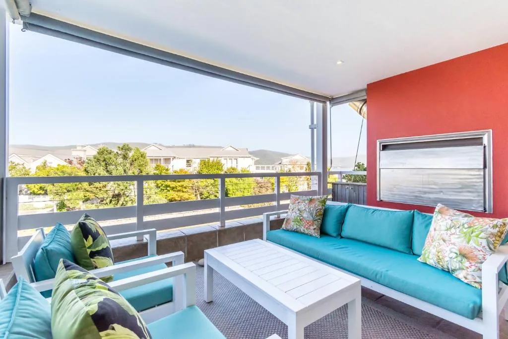 Modern deck with turquoise seating, ocean views, and coastal neighborhood landscape