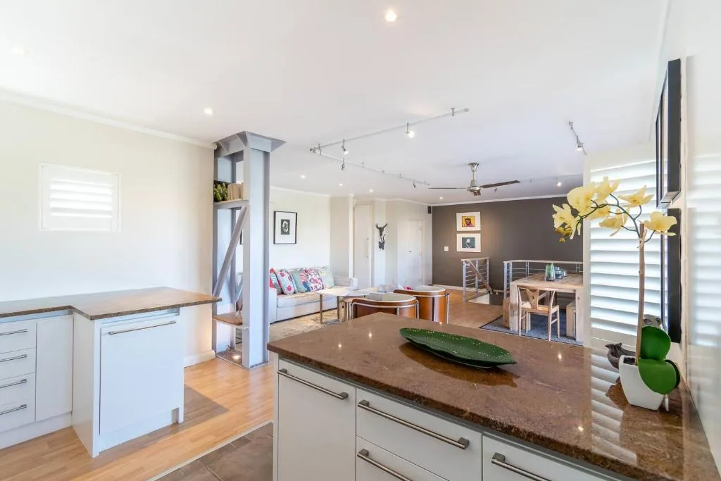 Modern kitchen with dark countertops, white cabinetry, and open-plan living area view