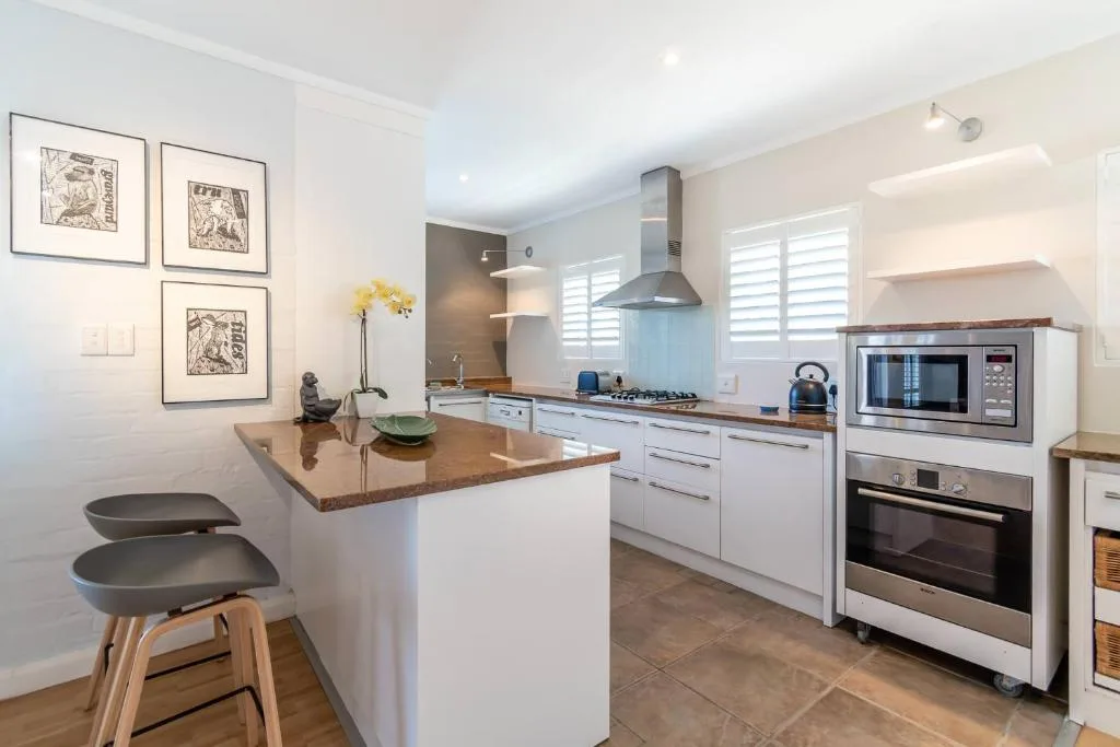 Modern kitchen with white cabinetry, island counter, stainless steel appliances
