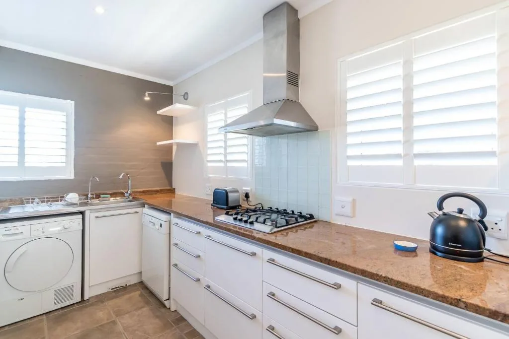 Modern kitchen with white cabinetry, stainless steel range hood, and granite countertops
