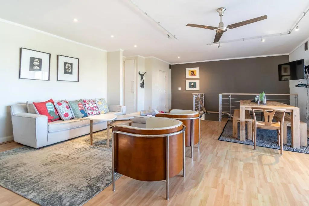 Open-plan lounge with cream sofa, colorful cushions, and modern wooden furniture