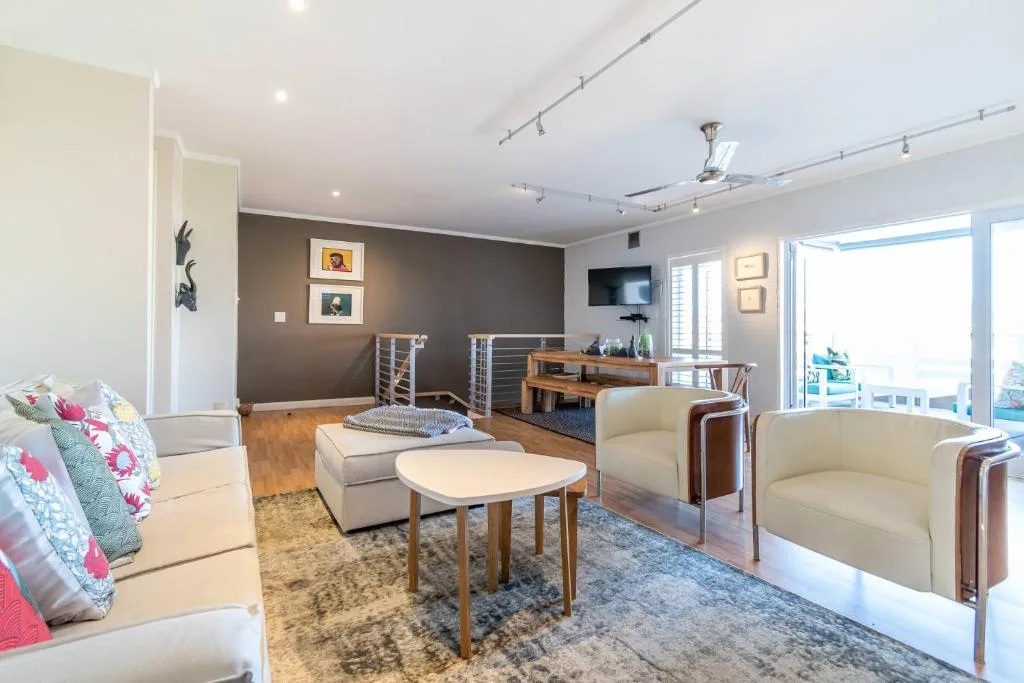 Modern living room with cream armchairs, wooden coffee table, and ocean view doors