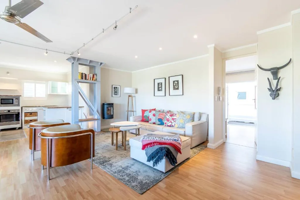 Spacious open-plan lounge with comfortable beige sofa and colorful cushions