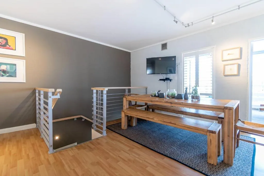 Modern lounge with wooden dining table, wall-mounted TV, and contemporary decor