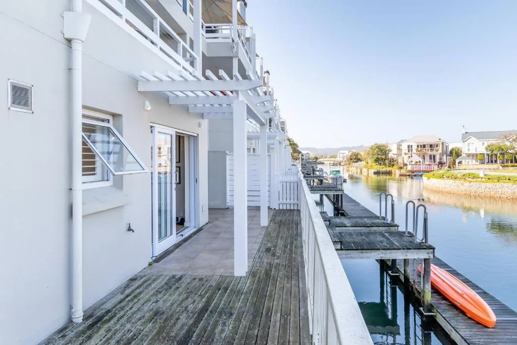 Waterfront deck with canal views, white pergola, and colorful kayak
