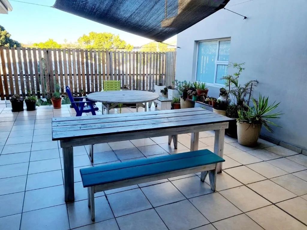Spacious patio with picnic tables, potted plants, and shade structure