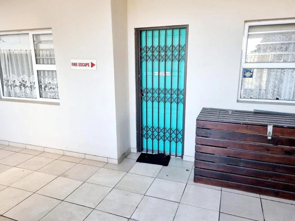 Bright turquoise security gate entrance with white walls and windows