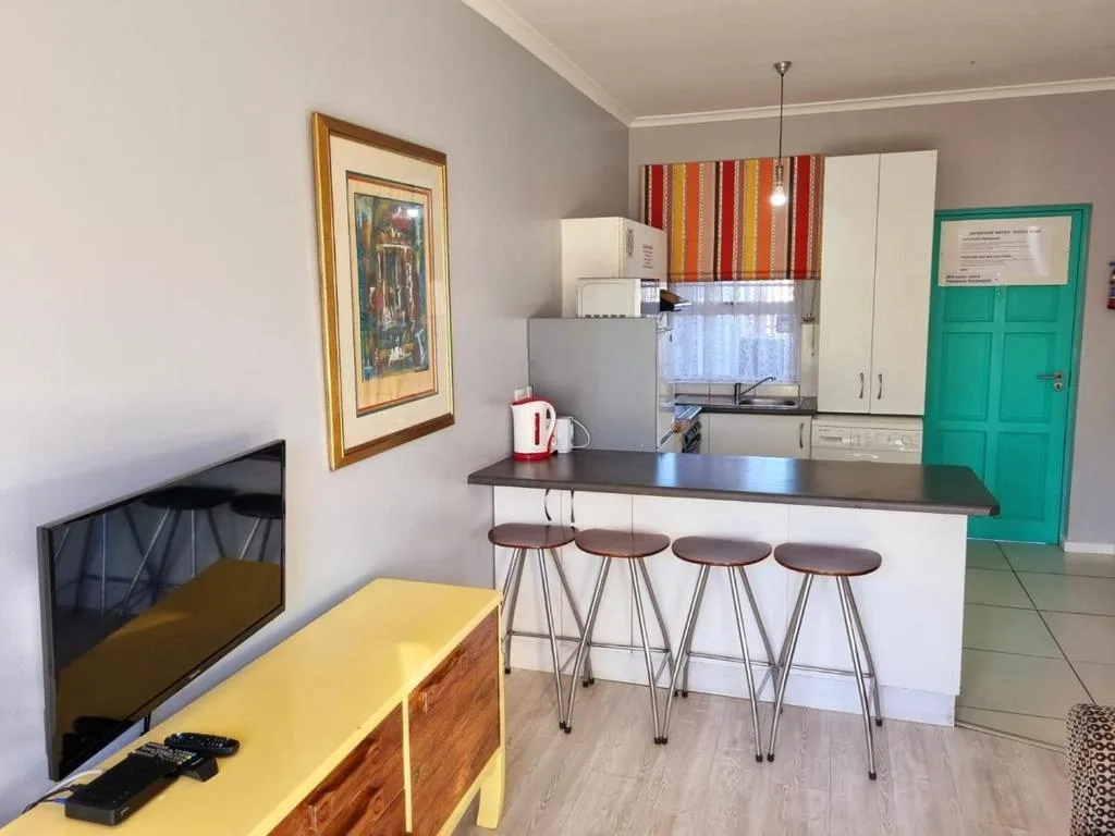 Open-plan lounge and kitchen with yellow accent furniture and bar seating