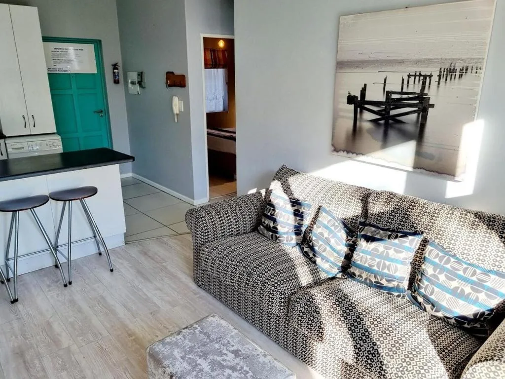 Open-plan lounge with gray sofa, decorative pillows, and coastal artwork on wall
