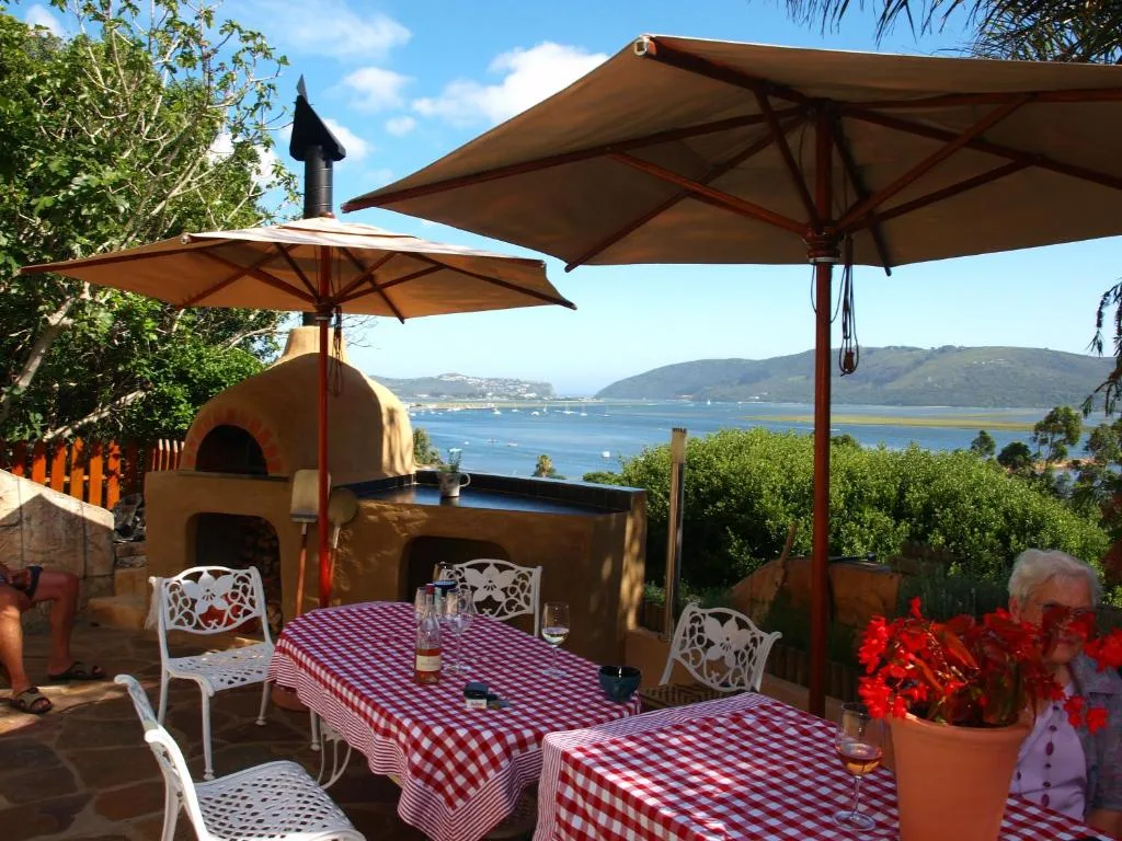 Outdoor dining area with umbrellas overlooking Knysna lagoon and mountains