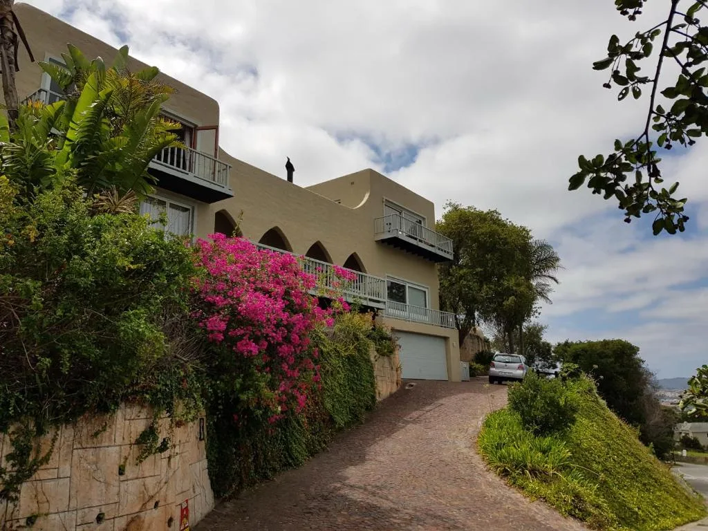 Modern beige apartment building with magenta bougainvillea, driveway, and garden landscaping