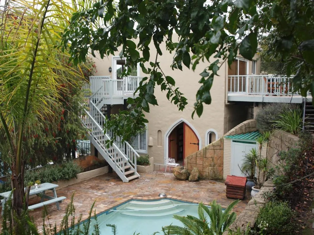 Beige building with white deck stairs and small courtyard pool surrounded by greenery