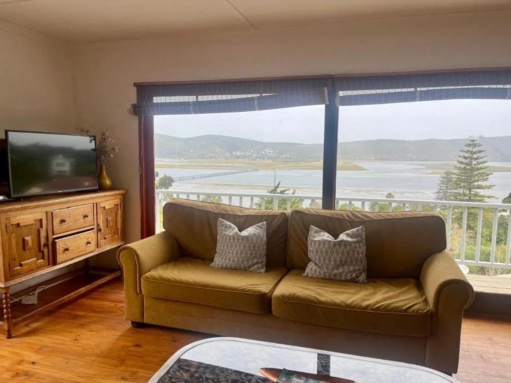 Comfortable lounge with sofa, TV, and scenic lagoon views through glass doors