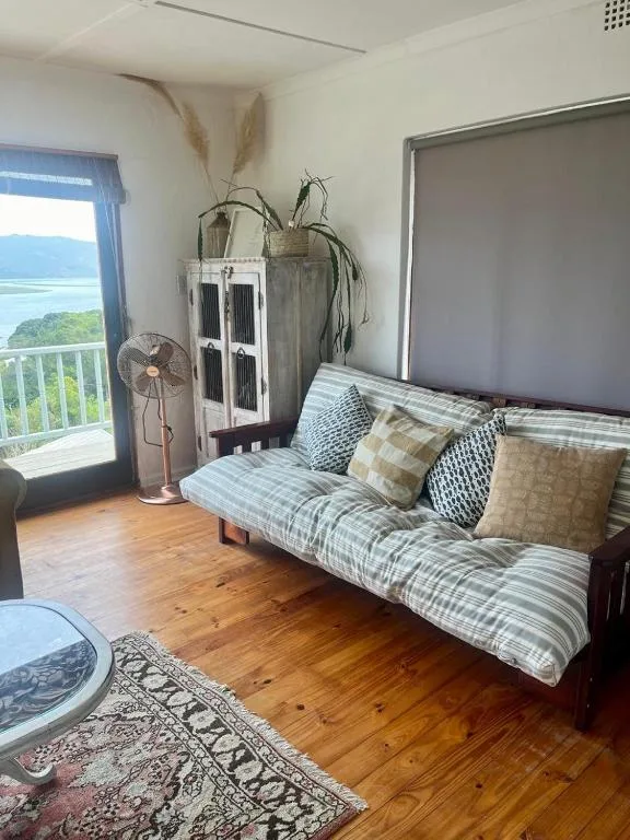 Living room with striped sofa, decorative pillows, and lagoon view through glass doors
