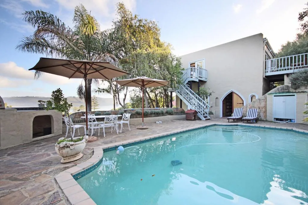Swimming pool with shaded seating area and lagoon view beyond