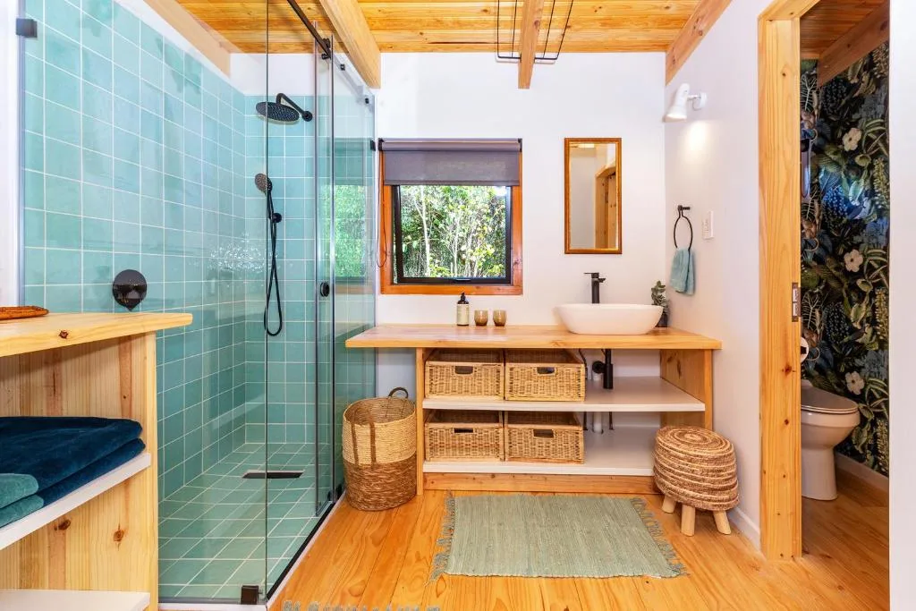 Modern bathroom with turquoise tile shower, wooden vanity, and natural light