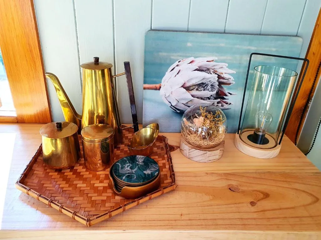 Decorative shelf display with brass vessels, coastal artwork, and home accessories