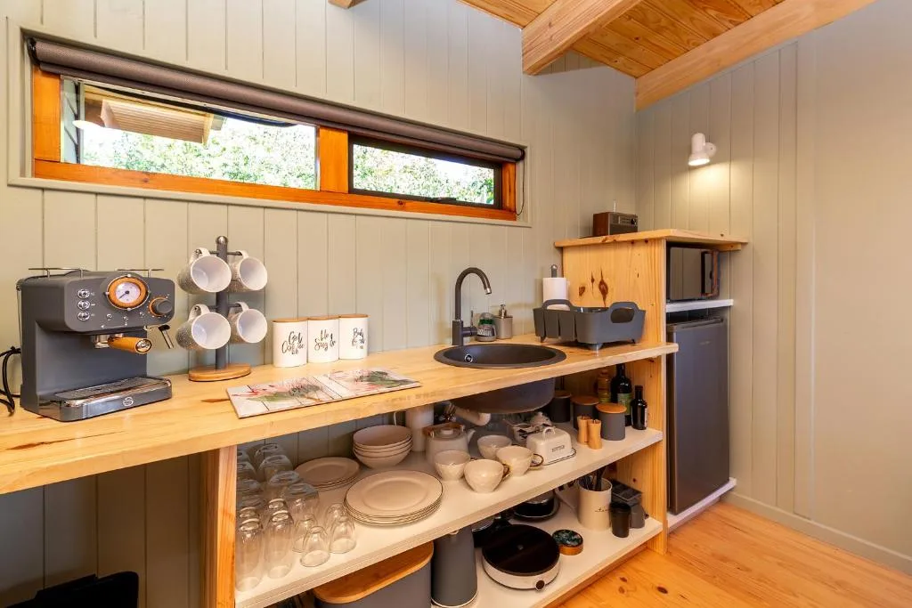 Modern kitchenette with wooden cabinetry, espresso machine, and organized dishware